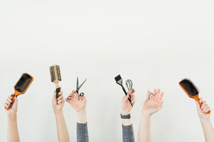hands raised holding hair care tools